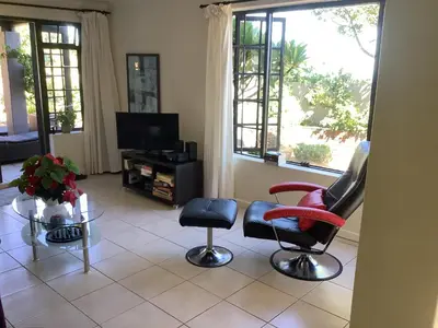 a living room with two chairs and a tv at Cozy Garden apartment with amazing view in Cape Town