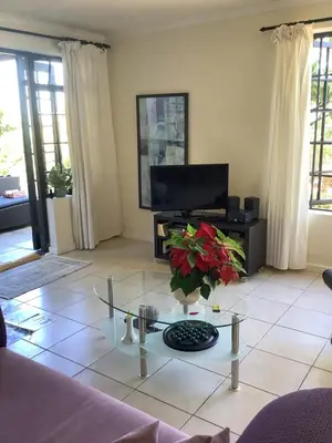 a living room with a glass coffee table and a tv at Cozy Garden apartment with amazing view in Cape Town