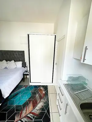 a room with a bed and a kitchen with a sink at Beatrice Guesthouse in Cape Town