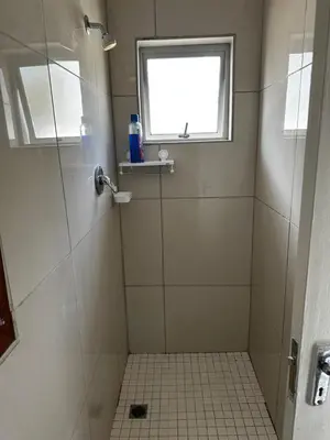a bathroom with a shower with a window at Beatrice Guesthouse in Cape Town
