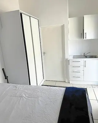 a white bedroom with a bed and a sink at Beatrice Guesthouse in Cape Town