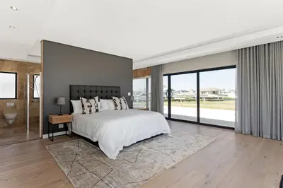 a bedroom with a large bed and large windows at Sunset Kite & Golf Villa in Cape Town
