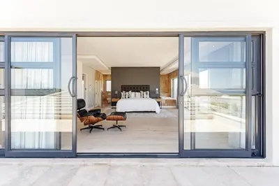 a bedroom with a bed and sliding glass doors at Sunset Kite & Golf Villa in Cape Town