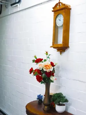 a vase with flowers on a table next to a clock at 33 Goulborn street Goodwood in Cape Town