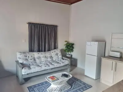 a living room with a couch and a refrigerator at La Maison Kuilsrivier in Cape Town