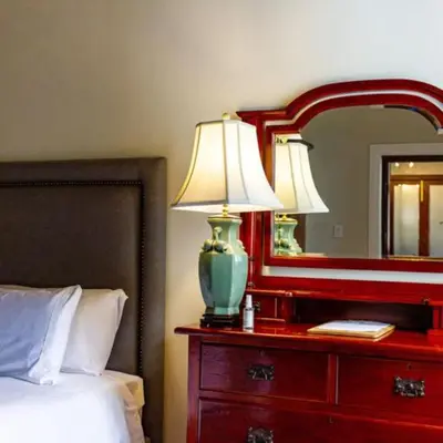 a bedroom with a red dresser with a lamp and a mirror at Plaisir Estate Accommodation in Simondium