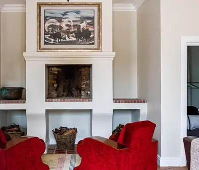 a living room with two red chairs and a fireplace at Plaisir Estate Accommodation in Simondium