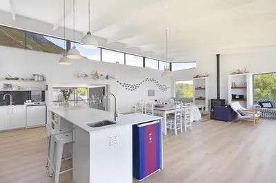 a kitchen and living room with white cabinets and a table at Suidersee-Voelklip in Hermanus