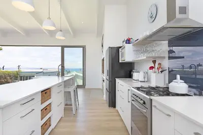 a kitchen with white counters and a large window at Suidersee-Voelklip in Hermanus