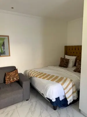 a bedroom with a bed and a couch in it at Mila Lodge 2 in Cape Town