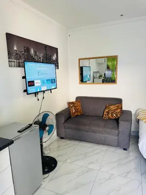 a living room with a couch and a flat screen tv at Mila Lodge 2 in Cape Town
