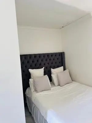 a bedroom with a large bed with white sheets and pillows at Mila Lodge 2 in Cape Town