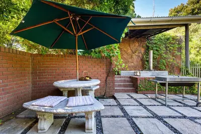 a table with an umbrella on a patio at Devon Castle Forest Lodge in Stellenbosch