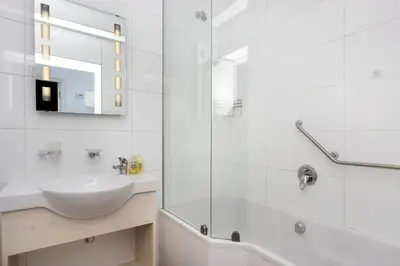 a white bathroom with a sink and a shower at Pips Place 301 in Strand