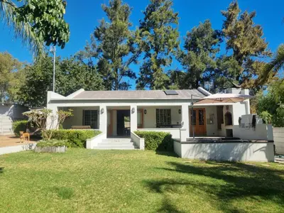 a white house with a yard at Alimandi Nursery Cottage in Cape Town