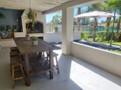 a dining room with a wooden table and an umbrella at Alimandi Nursery Cottage in Cape Town