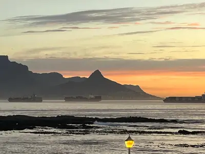 a street light in the water with mountains in the background at Sleepy Tides in Cape Town