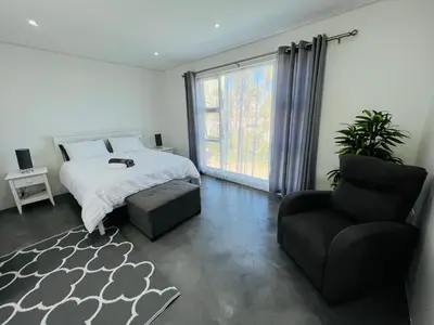 a bedroom with a bed and a chair and a window at Sleepy Tides in Cape Town