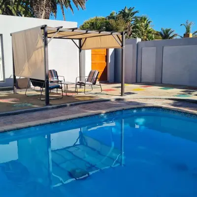 a swimming pool with chairs and an umbrella at 51 On Vlei in Cape Town