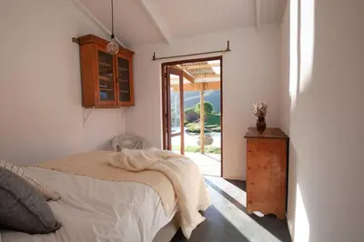 a bedroom with a bed and a door to a patio at Farmstay at the Goat Shed Cottage, Spinlea Farm in Greyton