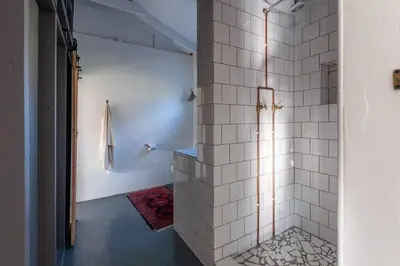 a bathroom with a shower with white tiled walls at Farmstay at the Goat Shed Cottage, Spinlea Farm in Greyton