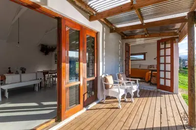 a wooden deck with a table and chairs on it at Farmstay at the Goat Shed Cottage, Spinlea Farm in Greyton