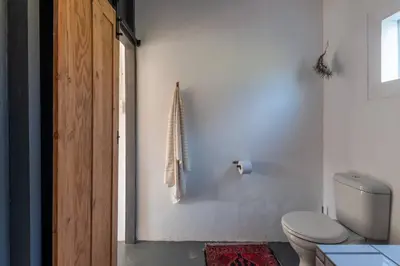 a bathroom with a toilet and a towel on the wall at Farmstay at the Goat Shed Cottage, Spinlea Farm in Greyton