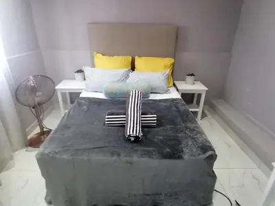 a bedroom with a large bed with yellow and blue pillows at Mila Lodge 1 in Cape Town