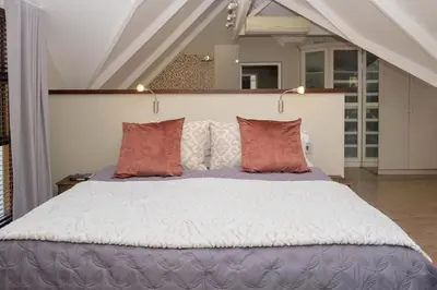 a bedroom with a large bed with red pillows at Eden-Paradys in Stellenbosch
