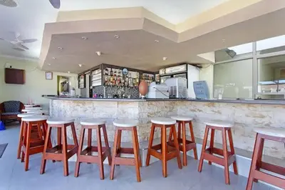a bar with a row of wooden stools in a restaurant at Ocean Breeze @ Hermanus Beach Club in Hermanus
