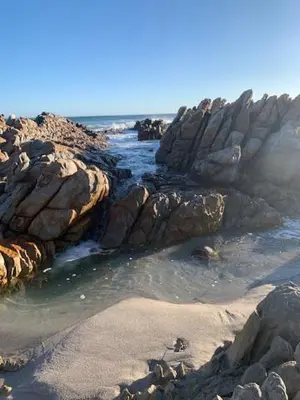 a group of rocks on a beach near the ocean at The Treehouse Suite in Hermanus