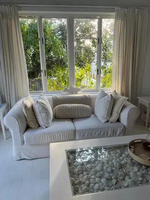 a living room with a white couch and a large window at The Treehouse Suite in Hermanus