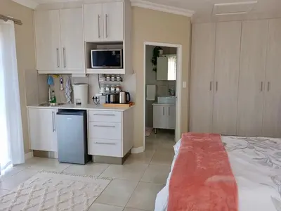 a kitchen with white cabinets and a counter top at 22's Company in Cape Town