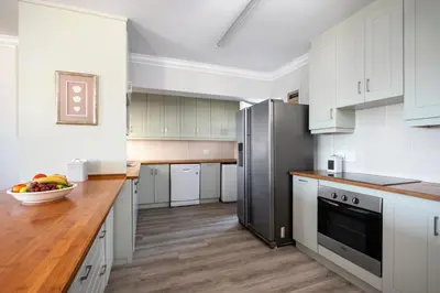 a kitchen with white cabinets and a stainless steel refrigerator at Wegbreek in Hermanus