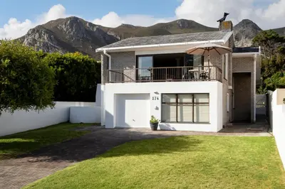 a white house with mountains in the background at Wegbreek in Hermanus