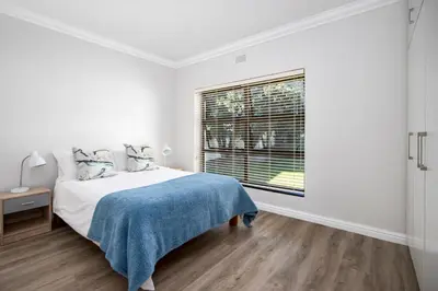 a white bedroom with a bed and a window at Wegbreek in Hermanus