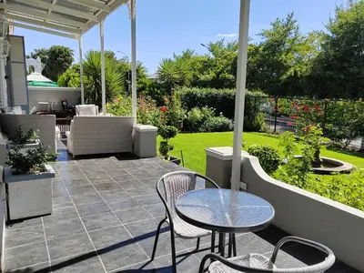 a patio with a table and chairs and a garden at La Damon 2 in Paarl