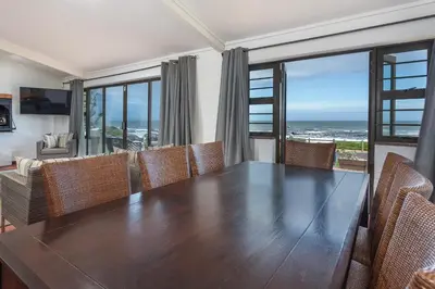 a dining room with a table and chairs and the ocean at The Atlantic in Onrus in Hermanus