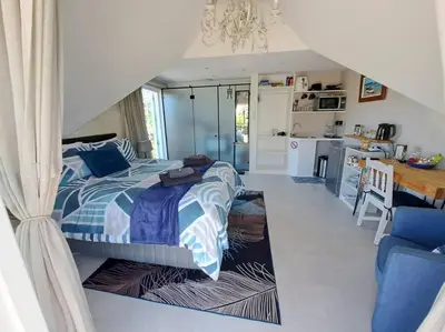 a bedroom with a bed and a kitchen with a table at Cape Dutch Flair Business unit in Cape Town