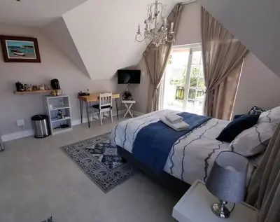 a bedroom with a bed and a table and a window at Cape Dutch Flair Business unit in Cape Town