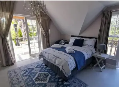 a bedroom with a large bed with a blue comforter at Cape Dutch Flair Business unit in Cape Town