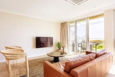 a living room with a couch and a table at Dolphin Beach cabana Luxe beach cabana voor 4 personen direct aan het strand in Table View