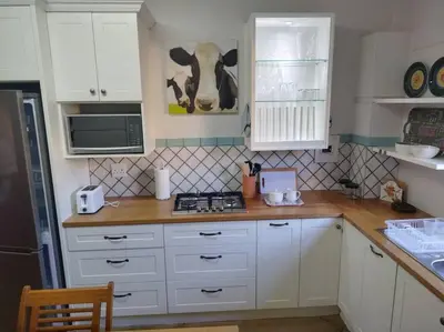 a kitchen with white cabinets and a cow hanging on the wall at Worcester Garden Cottage in Worcester