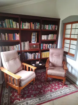 two chairs and a table in a room with book shelves at Worcester Garden Cottage in Worcester