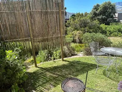 a garden with a table and chairs and a fence at The Annex in Pringle Bay