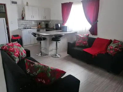 a living room with two couches and a kitchen at Kosies Nest Gastehuis in Cape Town