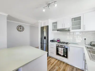 a kitchen with white cabinets and a white counter top at Tranquil Family Escape: Pool Balcony in Cape Town