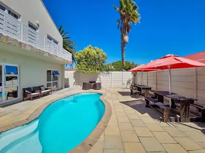 a swimming pool with a table and an umbrella at Tranquil Family Escape: Pool Balcony in Cape Town