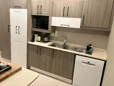 a kitchen with wooden cabinets and a sink and a dishwasher at Meerendahl Luxury Apartments at Heritage Square in Durbanville