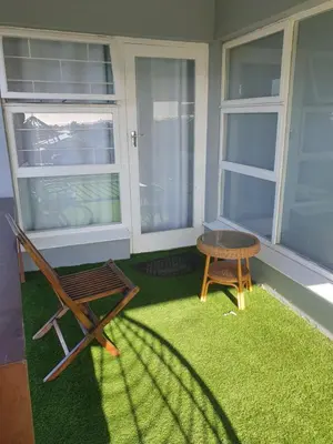 a porch with a chair and a bench on the grass at Gardenia Guesthouse in Cape Town